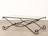 a glass coffee table with wrought iron legs and a glass top