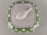 a white spoon sitting on a green and white plate