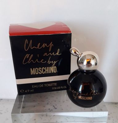 un flacon de parfum noir dans un coffret rouge, posé sur un comptoir en marbre