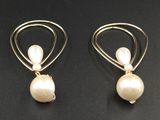 une paire de boucles d'oreilles en perles et en or posées sur un fond noir
