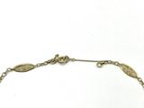a close up of a gold bracelet with a leaf design on it
