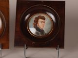 pair of miniature portraits of a gentleman and a woman on a wooden plaque