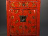 a red cabinet with gold leaf designs on the doors