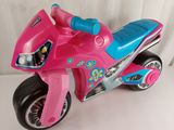 une moto jouet rose et bleue posée sur une table blanche