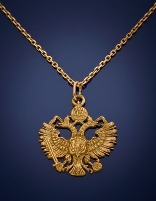 a gold necklace with a double headed eagle on it