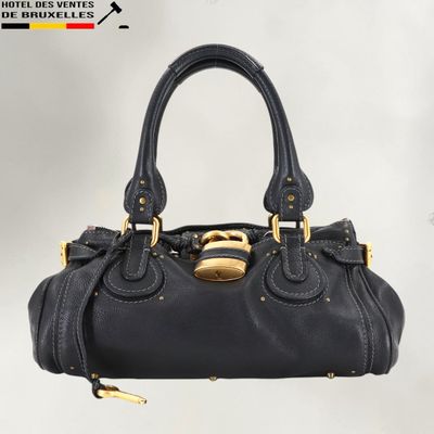 un sac à main en cuir noir muni d'une boucle dorée sur la poignée
