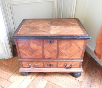 un petit coffre en bois monté sur roulettes, posé sur un parquet en bois dur