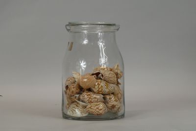 a glass jar filled with shells on a white surface
