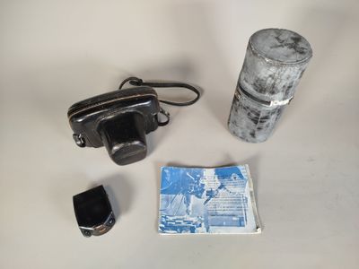 a camera, a canister, and a cigarette on a table