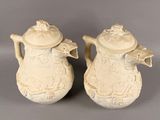 pair of cream colored ceramic vases with floral designs on them