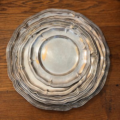 une assiette en argent posée sur une table en bois, à côté d'autres assiettes