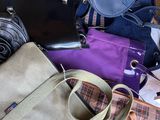 une pile de sacs à main et de sacs à bandoulière posée par terre