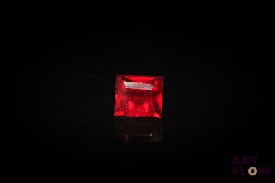 a square red ruby stone on a black surface