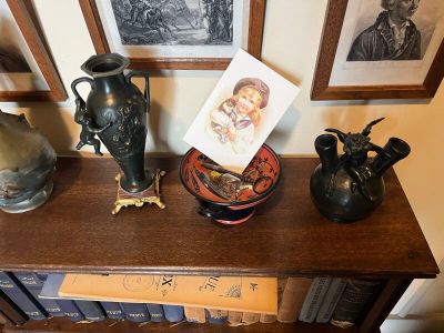 trois vases posés sur une étagère, avec des tableaux accrochés au mur derrière eux