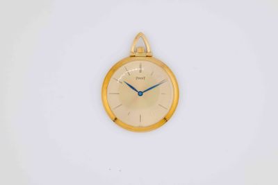 a gold clock on a white wall with a blue second hand