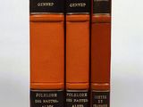 trois livres orange empilés les uns sur les autres sur une surface blanche