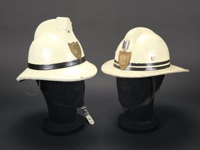 deux casques de pompier blancs posés sur une tête de mannequin noire