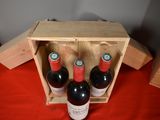 three bottles of wine in a wooden box on a table