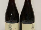 two bottles of red wine sitting next to each other on a table