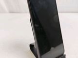 a black cell phone on a stand on a white surface