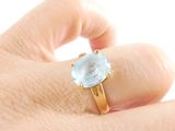 a person ' s hand holding a ring with a blue stone on it