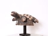 sculpture représentant une tortue couchée sur un morceau de bois posé sur un socle