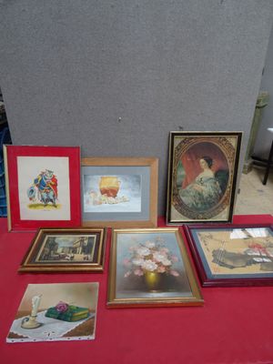 many framed pictures on a red table with a red table cloth