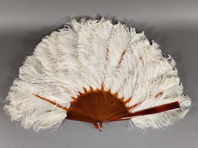 white and brown ostrich fan with wooden handle on grey background