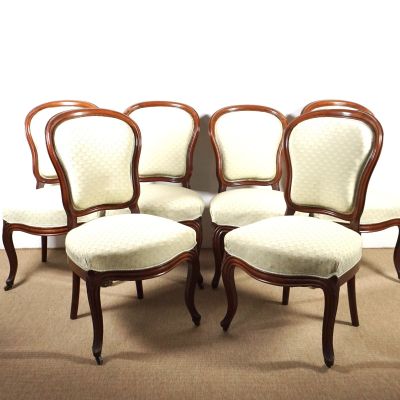 quatre chaises à assise rembourrée sont alignées contre un mur blanc
