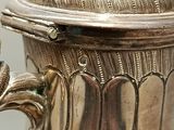 a silver vase with a lid sitting on a table