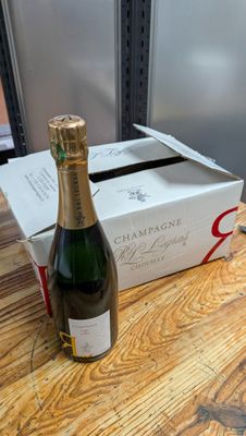 une bouteille de champagne posée sur une table à côté d'un carton de vin