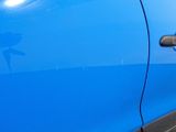 a close up of a blue car door handle with a sticker on it