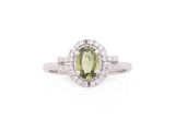 gros plan d'une bague avec une pierre verte entourée de diamants blancs