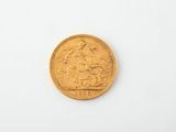 a gold sovereign coin on a white surface