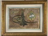 tableau représentant une calligraphie arabe dans un cadre doré, accroché au mur