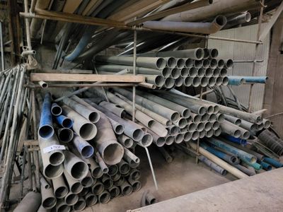 a large pile of pipes stacked up in a warehouse