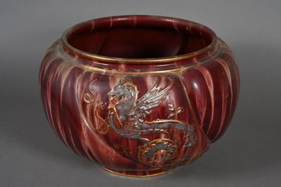 un vase rouge orné d'un dragon, posé sur une table