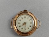 a small gold pocket watch with roman numerals on the face