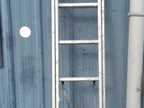 une échelle appuyée contre un mur bleu, à côté d'un tuyau