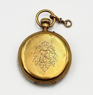 une montre de poche en or avec une chaîne, posée sur une surface blanche