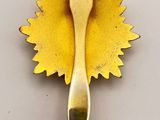 yellow leaf shaped broocher with a metal spoon in the middle of it