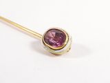 a close up of a gold stick with a pink stone on it