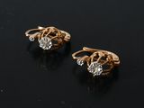 pair of gold and diamond earrings on a black surface