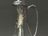 a clear glass pitcher with a silver handle on a table