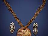 a close up of a necklace and earrings on a blue background