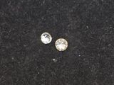 a pair of diamond stud earrings on a black surface