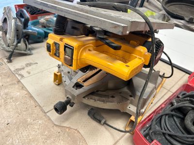 une scie circulaire jaune posée sur une table, à côté d'autres outils
