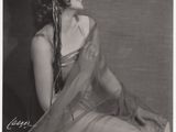 photographie en noir et blanc d'une femme en robe, assise sur un lit
