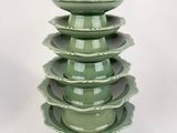 a tall green vase that has five plates stacked on top of it