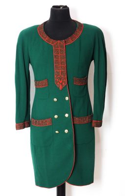 une veste verte avec des bordures rouges et des boutons dorés, présentée sur un mannequin